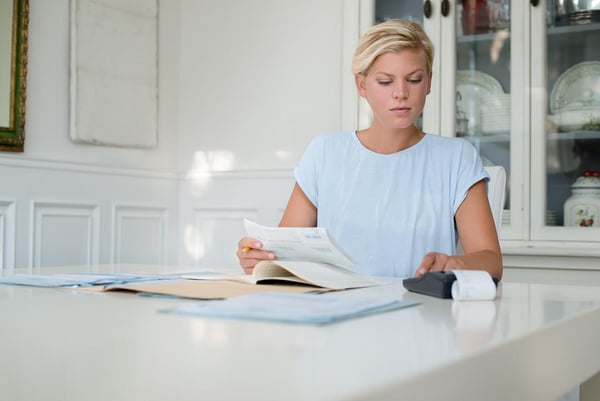 Young woman checking bills and doing budget at home Loan Increases Out of Sync with Education Goals