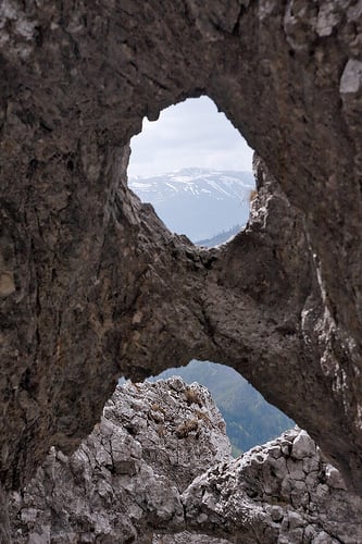 Snowy mountain summit through hole in rocky wall